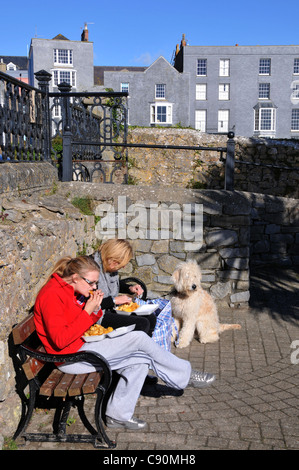 Due donne sedeva sul lungomare a mangiare pesce e patatine, Tenby, Pembrokeshire, a sud del Galles Wales, Gran Bretagna Foto Stock