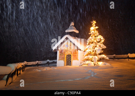 Cappella con albero di natale a nevicata, Elmau, Alta Baviera, Germania, Europa Foto Stock