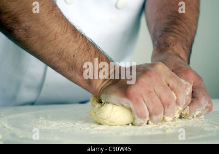 Un baker massaggia di pasta di pane prima della cottura. Foto Stock