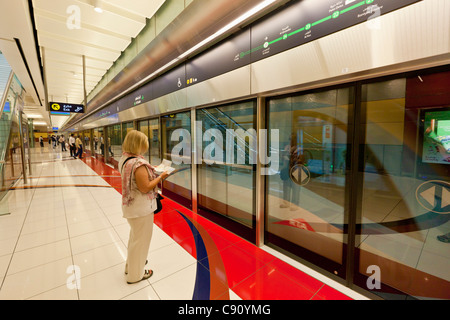 Donna che legge un libro guida sulla piattaforma della metropolitana al fahidi la stazione della metropolitana di Dubai, Emirati Arabi Uniti, Emirati arabi uniti, Medio Oriente Foto Stock