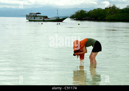 Donna turistica di fotografare la vita di mare, Raja Ampat isole vicino Papua occidentale, in Indonesia nel triangolo di corallo, Oceano Pacifico. Foto Stock