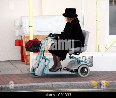 Ben vestito donna senior in nero sulla mobilità scooter, Eastbourne, East Sussex, England, Regno Unito Foto Stock