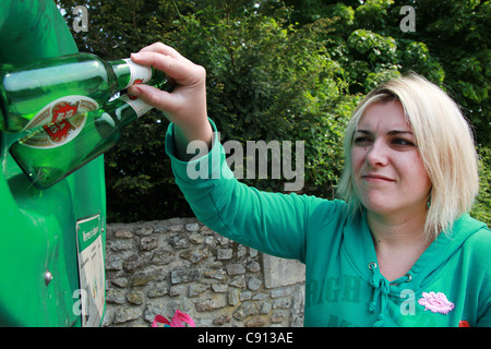 Giovane donna utilizzando una bottiglia bank Foto Stock