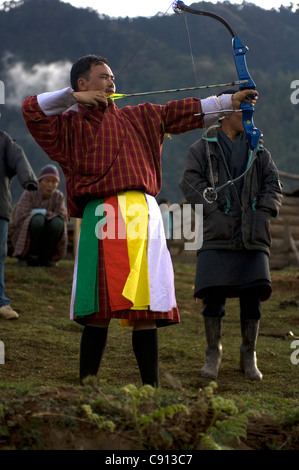 Un arciere prende la mira durante una tre giorni di inter-villaggio tiro con l'arco contest at Gangtey nella valle di Phobjika del Bhutan. Foto Stock