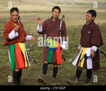 Ogni volta che qualcuno colpisce il bersaglio, i membri del team in un inter-villaggio tiro con l'arco contest in Bhutan fare una canzone e la danza di routine. Foto Stock