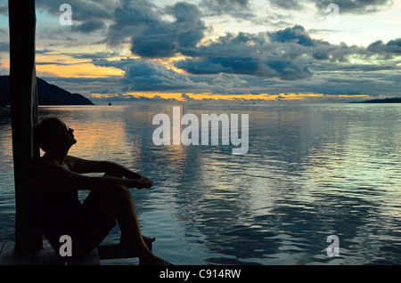 Persone di mezza età uomo europeo rilassante al tramonto sul molo Kri Raja Ampat isole della Papua occidentale nell'Oceano Pacifico, Indonesia. Foto Stock