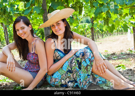 Donna sorridente seduta mediante una struttura ad albero in Orchard Foto Stock