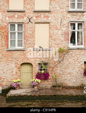 Molti di Bruges storica case mercantili parte anteriore su una complessa rete di canali che sono stati utilizzati come vie commerciali in tempi passati Foto Stock