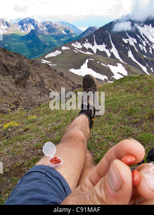 Trail runner appoggia e prende ibuprofene in parte anteriore Chugach Mountains, nei pressi di ancoraggio, Chugach State Park in Alaska centromeridionale Foto Stock