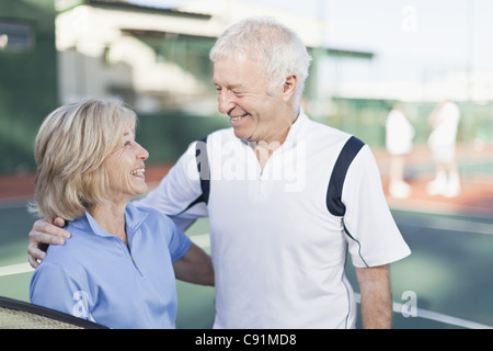 Coppia di anziani abbracciando sul campo da tennis Foto Stock