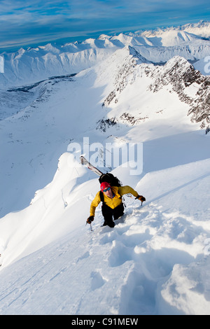 Sciatore sale elevato per gli sci il ripido fronte sud-ovest del monte Kickstep, Turnagain Pass, Kenai Mountains in Alaska centromeridionale Foto Stock