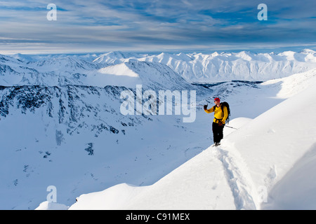 Sciatore sale elevato per gli sci il ripido fronte sud-ovest del monte Kickstep, Turnagain Pass, Kenai Mountains in Alaska centromeridionale Foto Stock