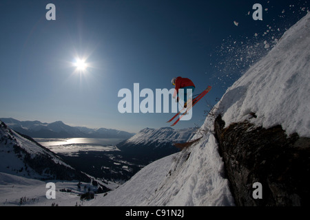 Silhouette di una discesa sciatore fa un salto estremo da una battuta mentre sci presso Alyeska Resort, centromeridionale Alaska, inverno Foto Stock