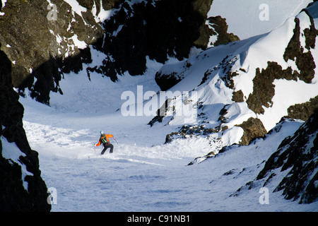 L'uomo backcountry sci alpinismo sul fronte nord del picco Korohusk nella Ram Valley, Chugach Mountains, Eagle River, Alaska Foto Stock