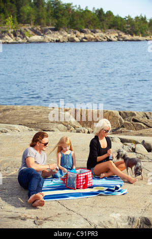 Famiglia avente picnic sulle rocce dal lago Foto Stock