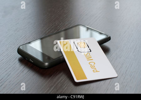 La carta SIM e il telefono cellulare sul tavolo Foto Stock