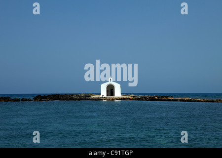 Vi è una piccola cappella bianca di fronte al mare a Georgioupolis, raggiunto da una pietra causeway, chiamato Agios Nikolaos. Foto Stock