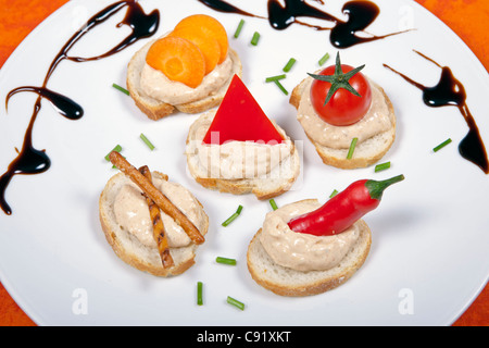 Liptauer crema di formaggio, servita su fette di baguette, decorata con frutta e salatini Foto Stock