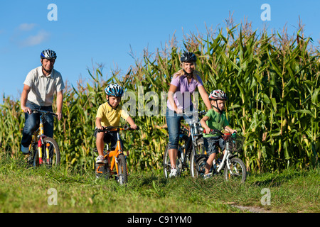 La famiglia è la bicicletta in estate - padre, madre e due figli Foto Stock