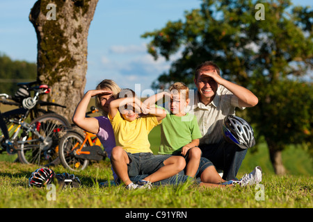 La famiglia felice (padre, madre e due figli) sulla via di fuga con la bici - hanno una pausa Foto Stock