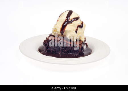 Salsa al cioccolato brownie con gelato alla vaniglia e una pioggerellina di salsa al cioccolato su sfondo bianco intaglio Foto Stock