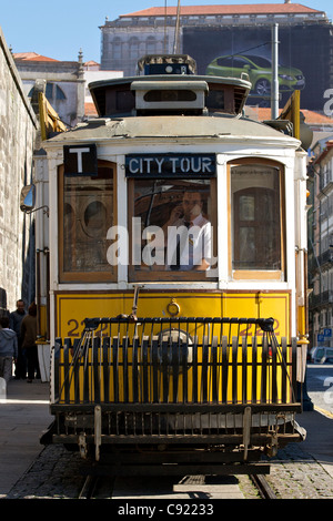 Tram gialli con griglie anteriori viaggiare su visite guidate della città sulle colline ripide nella città vecchia. Porto, Portogallo. Foto Stock