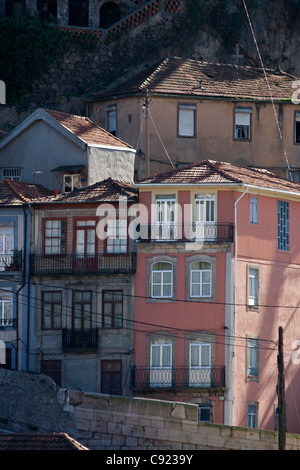 Cinque piani di case con balconi in ombra del ponte Dom Luis primo ponte sulla sponda nord del fiume Douro a Porto Foto Stock