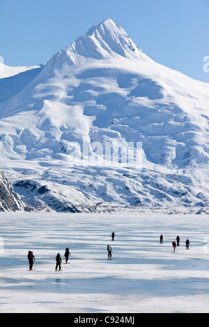 Un gruppo di appassionati di sci ski attraverso congelati Lago Portage con supporto Bard in background, centromeridionale Alaska, molla Foto Stock