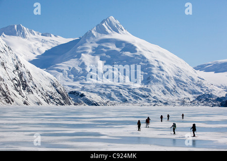 Un gruppo di appassionati di sci ski attraverso congelati Lago Portage con supporto Bard in background, centromeridionale Alaska, molla Foto Stock