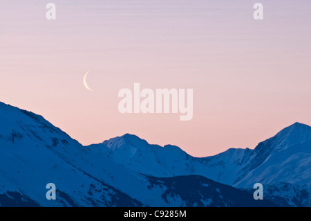 Cresent luna sorge all'alba sopra il Kenai Mounatins lungo il braccio Turnagain centromeridionale, Alaska, molla Foto Stock