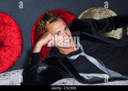 Uomo sorridente indossando la corona di plastica in bar Foto Stock