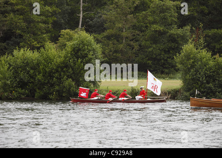 Tomaie di Swan nel loro tradizionale scarlet uniforme skiffs riga giù il fiume durante il cigno batte in volata, il fiume Tamigi e Henley, Inghilterra Foto Stock