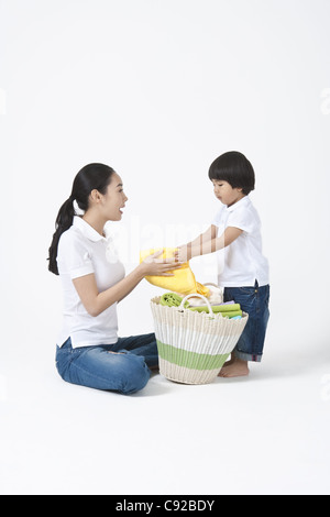 Figlio aiutando la madre a mantenere gli asciugamani nel cestello Foto Stock