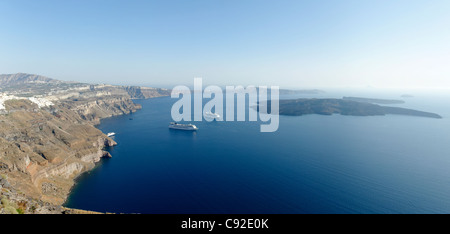 Vista panoramica della vasta caldera di Santorini con navi da crociera nel suo mare azzurro. A sinistra si trova la capitale imbiancate Fira. Foto Stock