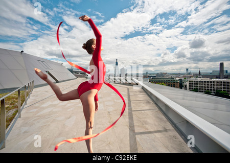 Ballerina con fiocco sul tetto urbano Foto Stock