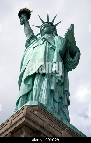 Guardando verso l'alto la Statua della Libertà con i turisti di sbirciare da dietro la mensola a piedistallo Foto Stock