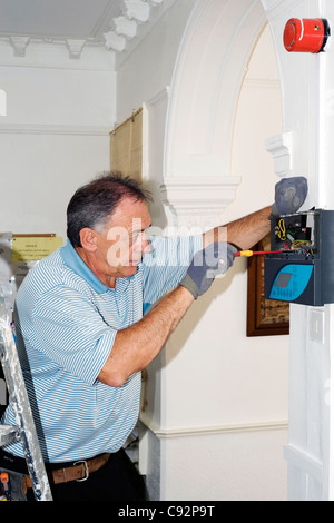 Elettricista lavorando su una sicurezza sistema di illuminazione in una casa Foto Stock