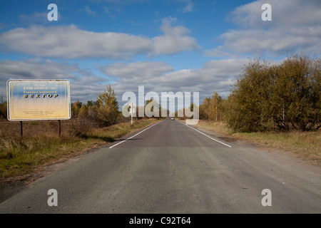 Strada vuota con segno a spiovente in 10 km Zona di esclusione di Chernobyl in Ucraina Foto Stock