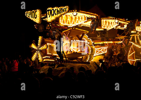 Galleggianti illuminata di notte con musica durante il bridgwater stagione di carnevale con gli spettatori che fiancheggiano le strade Foto Stock