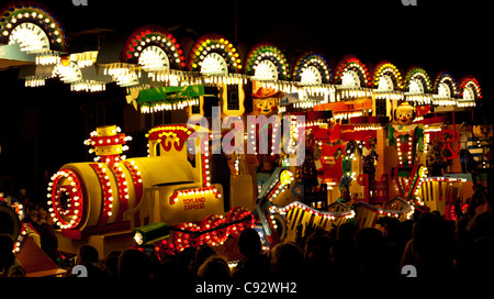 Galleggianti illuminata di notte con musica durante il bridgwater stagione di carnevale con gli spettatori che fiancheggiano le strade Foto Stock