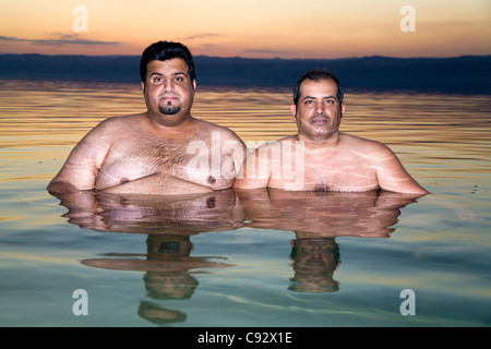 Due uomini giordani / maschio / uomo turistico / turisti relax ad alto contenuto di sale / salato l'acqua salata del Mar Morto lago. Foto Stock