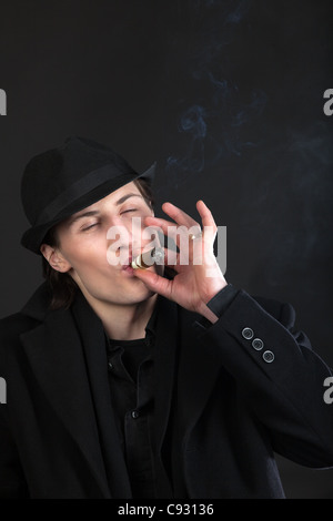 Uomo in tessuto nero e hat sigaro di fumo con gusto Foto Stock