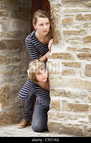 Due ragazze spiata attraverso la porta della vecchia chiesa Foto Stock