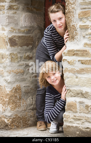 Due ragazze spiata attraverso la porta della vecchia chiesa Foto Stock