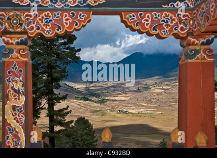 Una vista della fertile valle Phobjikha incorniciato nel balcone decorato di una casa bhutanesi. Foto Stock