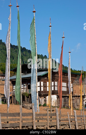 Una casa colonica con bandiere di preghiera nella fertile valle Phobjikha. Foto Stock