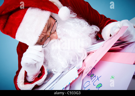 Immagine di Santa Claus nella parte anteriore del mucchio di lettere la lettura di uno di essi Foto Stock