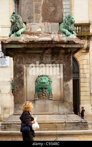 Arles; Bouches du Rhone, Francia; una donna passando davanti ad un dettaglio della base della obelix a Place de la Republique Foto Stock