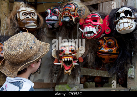 Bali Ubud. Un giovane turista ispeziona i tradizionali maschere Balinese in un mercato in stallo. Signor Foto Stock