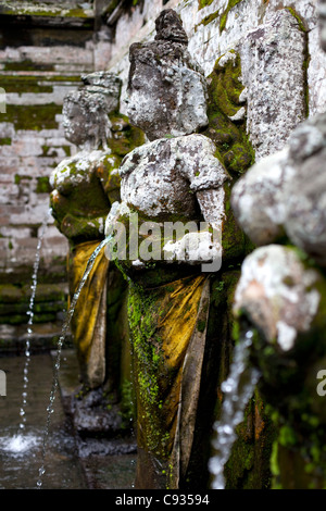 Bali Ubud. Antiche statue di granito versare acqua nella piscina di balneazione di Goa Gajah Elephant tempio nella grotta. Foto Stock